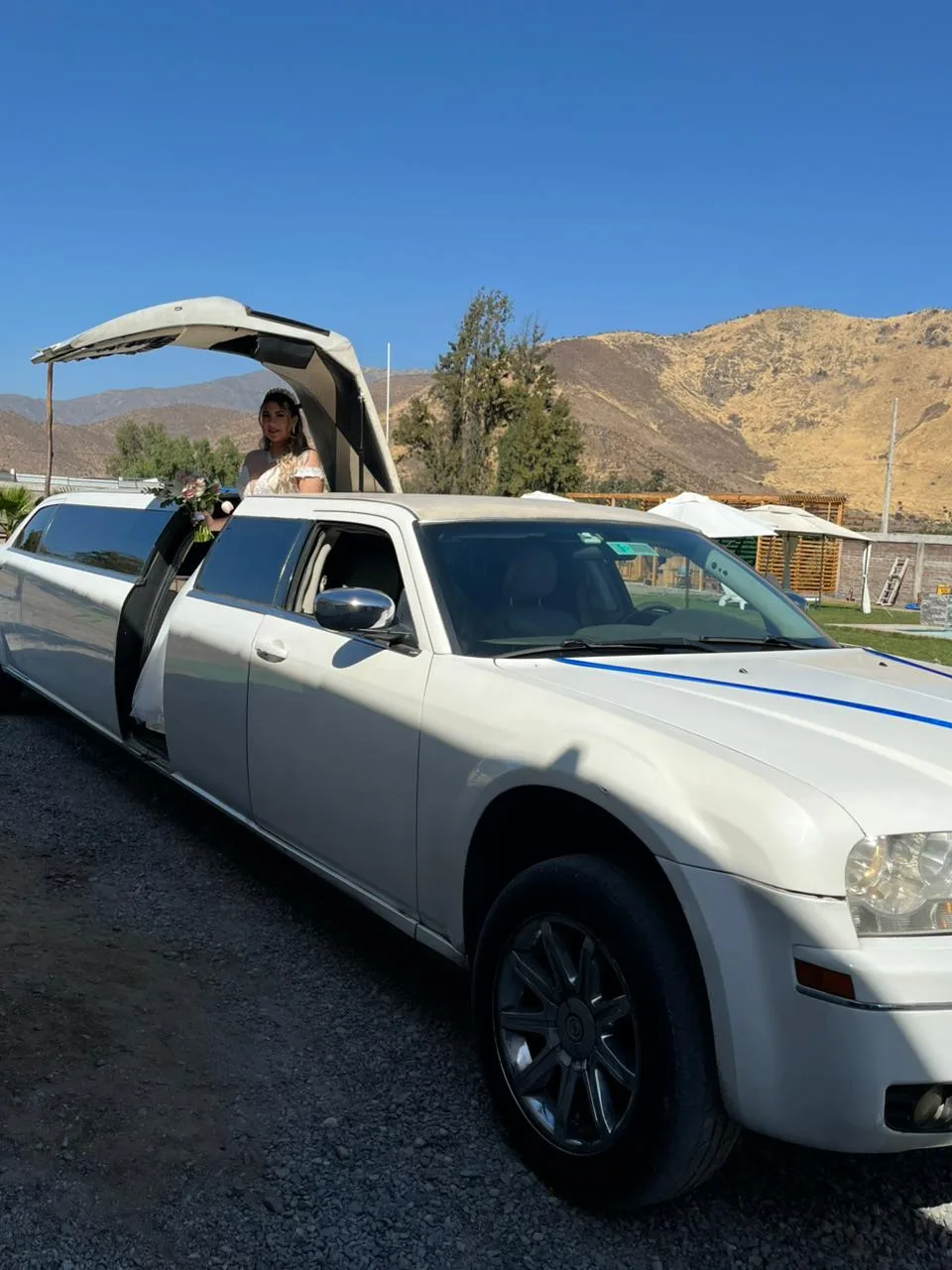 Novia junto a auto para matrimonio en Santiago, Chrysler blanco